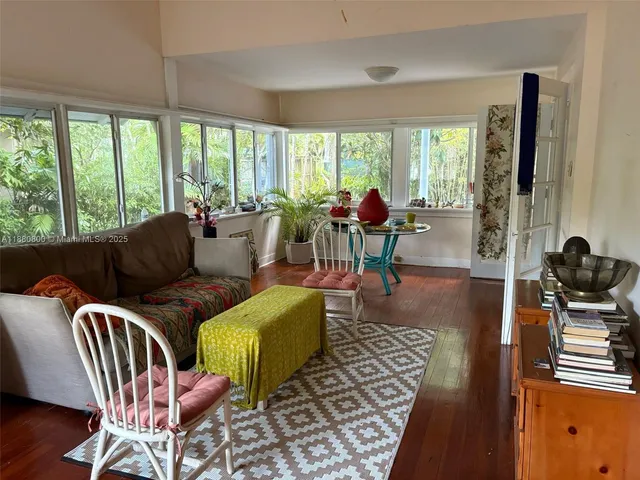 a view of a hallway with couches and dining table with wooden floor
