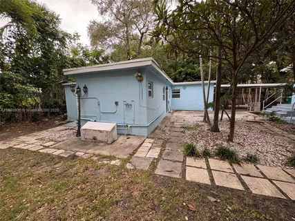 a view of a house with a yard chairs and wooden fence