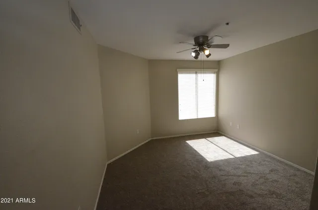 an empty room with windows and fan