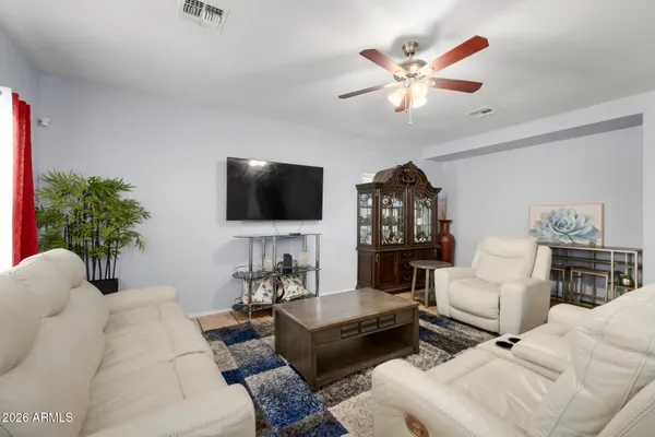 a living room with furniture a ceiling fan and a flat screen tv