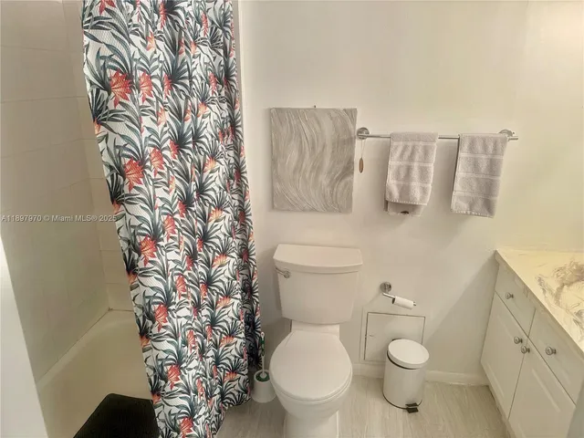 a white toilet sitting next to a shower curtain