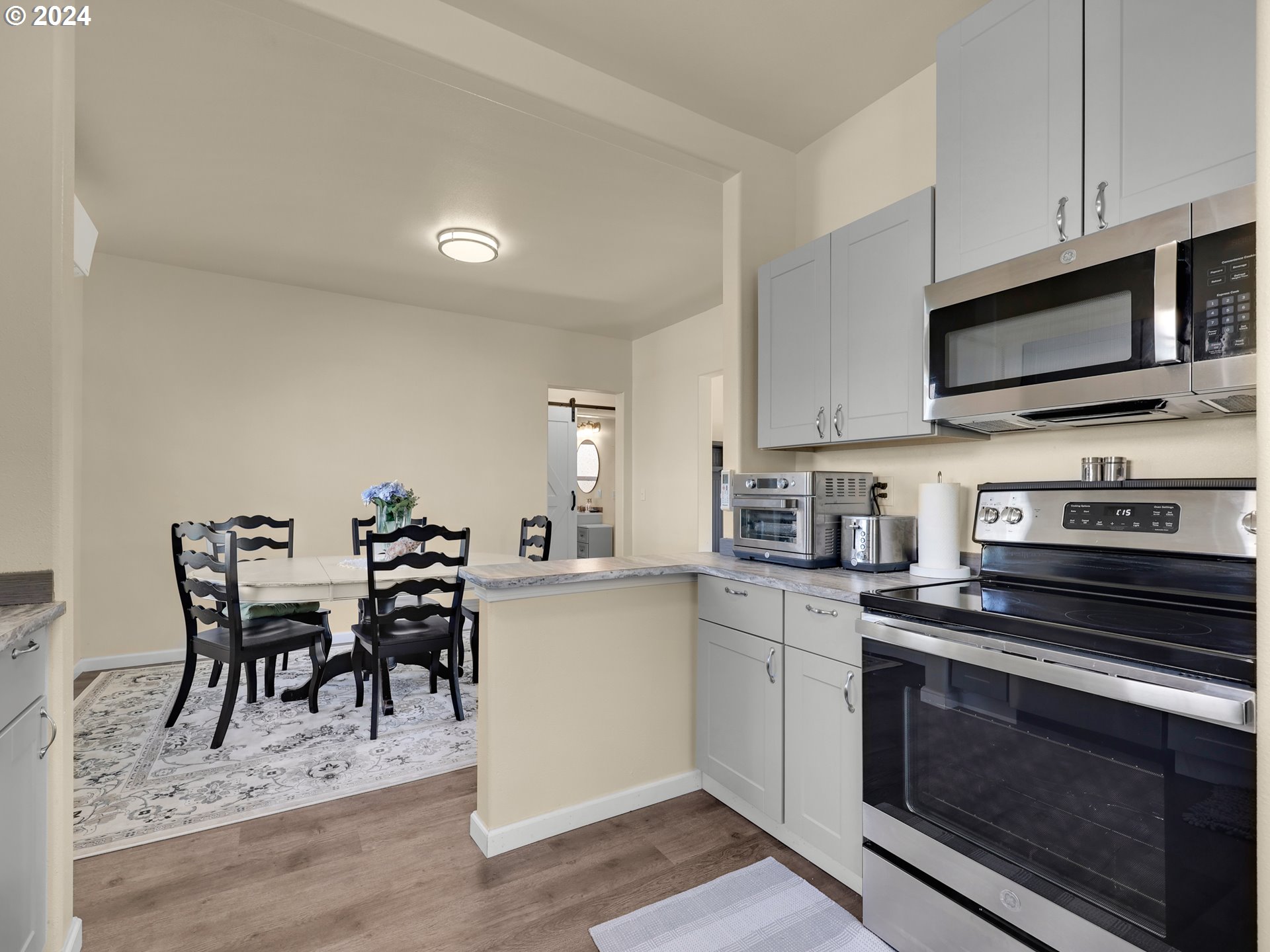 118 Main Street Southwest Ilwaco, WA 98624 - Photo 16 of 44 a kitchen with stainless steel appliances kitchen island granite countertop a dining table chairs stove and white cabinets