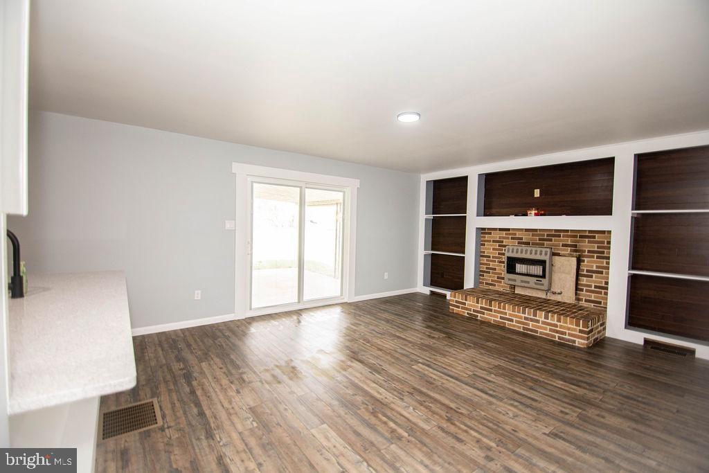 245 Windy Hill Road Shermans Dale, PA 17090 - Photo 21 of 42 an empty room with wooden floor fireplace and windows