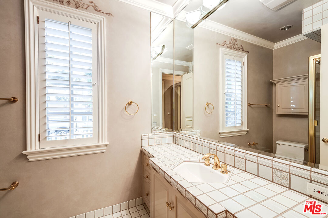 10045 Valley Spring Lane Toluca Lake, CA 91602 - Photo 19 of 36 a bathroom with a granite countertop sink and a mirror