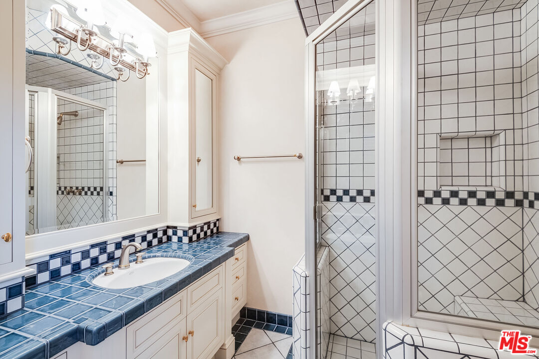 10045 Valley Spring Lane Toluca Lake, CA 91602 - Photo 21 of 36 a bathroom with a sink a mirror and shower