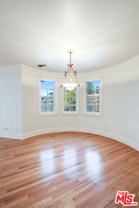 10045 Valley Spring Lane Toluca Lake, CA 91602 - Photo 31 of 36 an empty room with wooden floor chandelier fan and windows