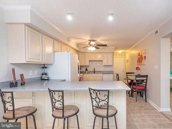 a kitchen with stainless steel appliances kitchen island granite countertop a table chairs sink and cabinets