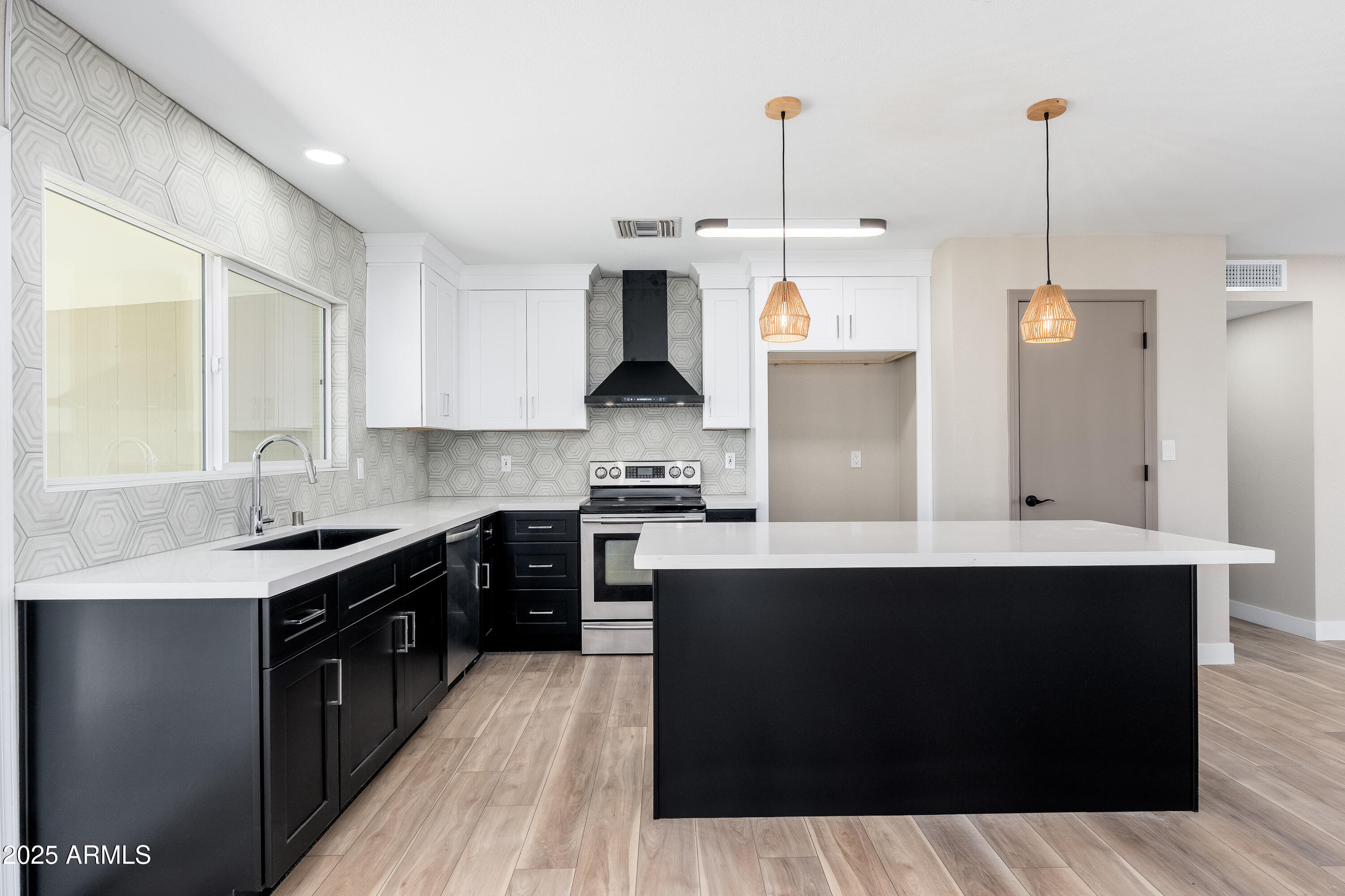a kitchen with stainless steel appliances granite countertop a sink a stove and a wooden floor