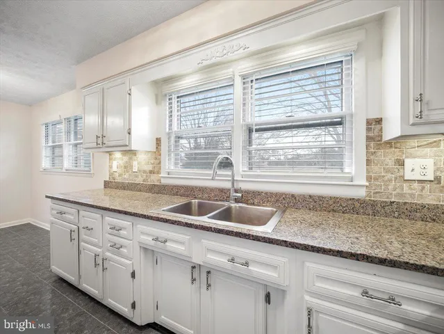 a kitchen with granite countertop a sink a window and cabinets