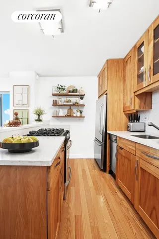 a kitchen with stainless steel appliances a sink dishwasher a refrigerator a stove and white cabinets with wooden floor