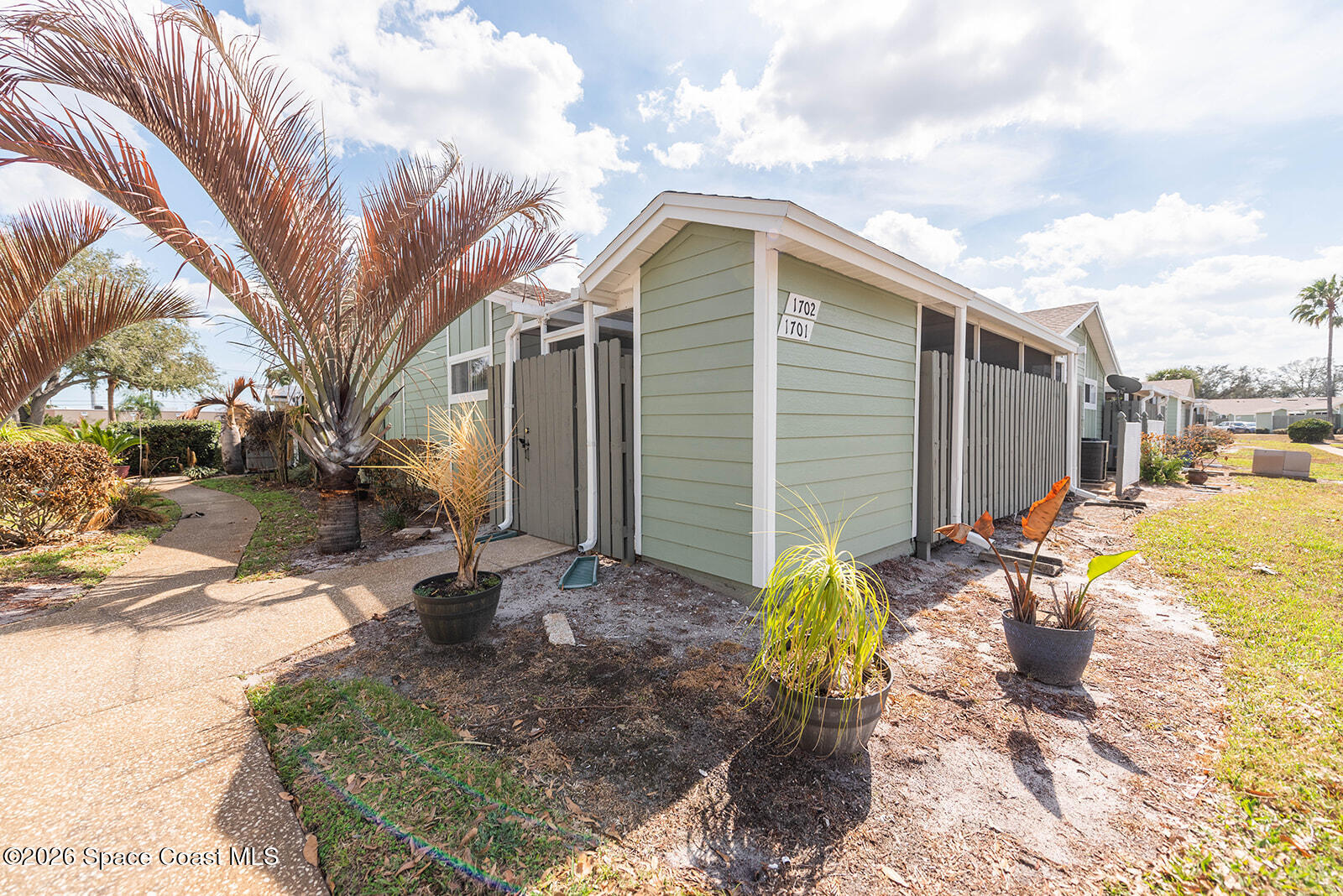 1954 Quail Ridge Court, Unit 1701 Cocoa, FL 32926 - Photo 2 of 41 a backyard of a house with large trees and barbeque oven