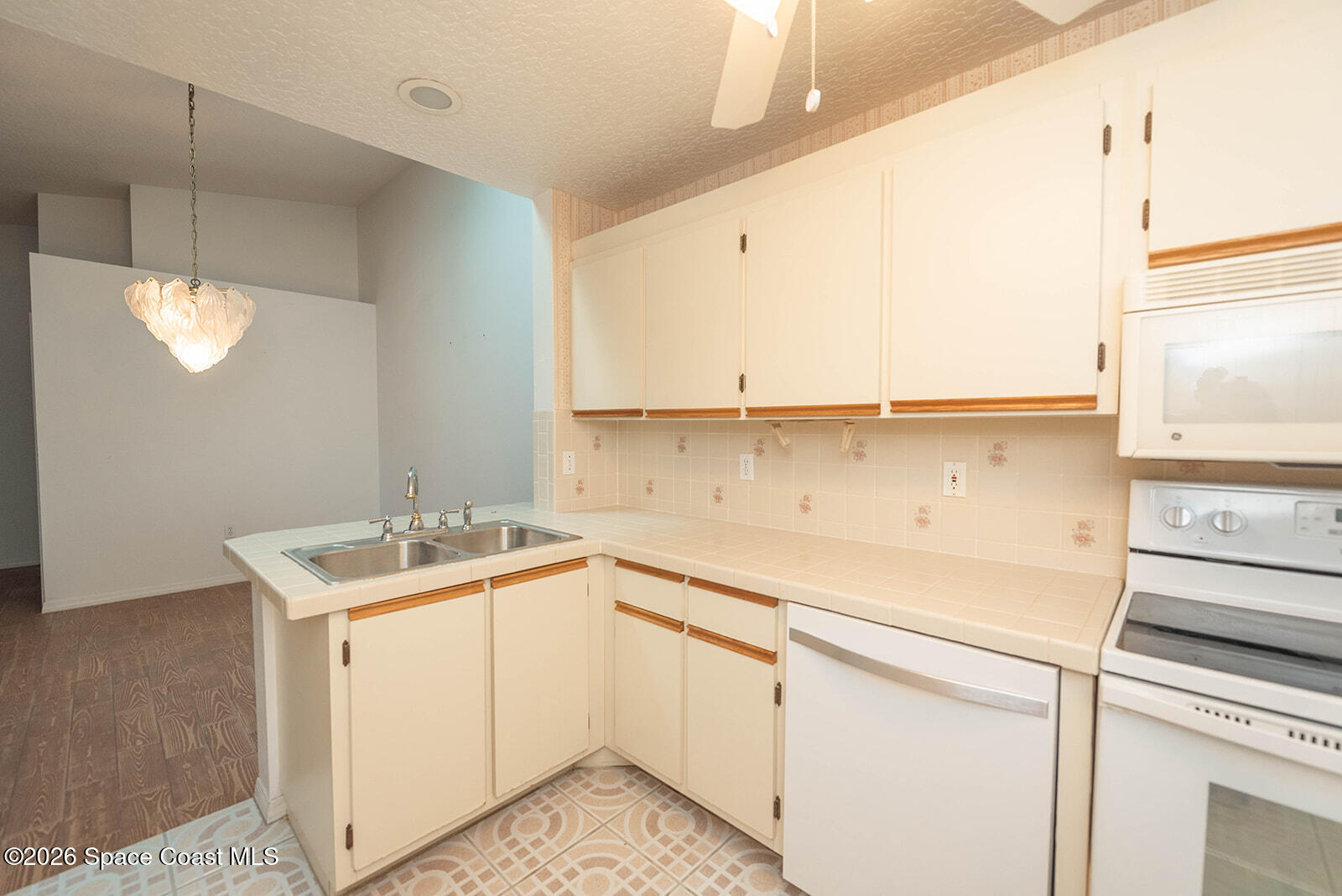 1954 Quail Ridge Court, Unit 1701 Cocoa, FL 32926 - Photo 36 of 41 a kitchen with a sink dishwasher and white cabinets with wooden floor