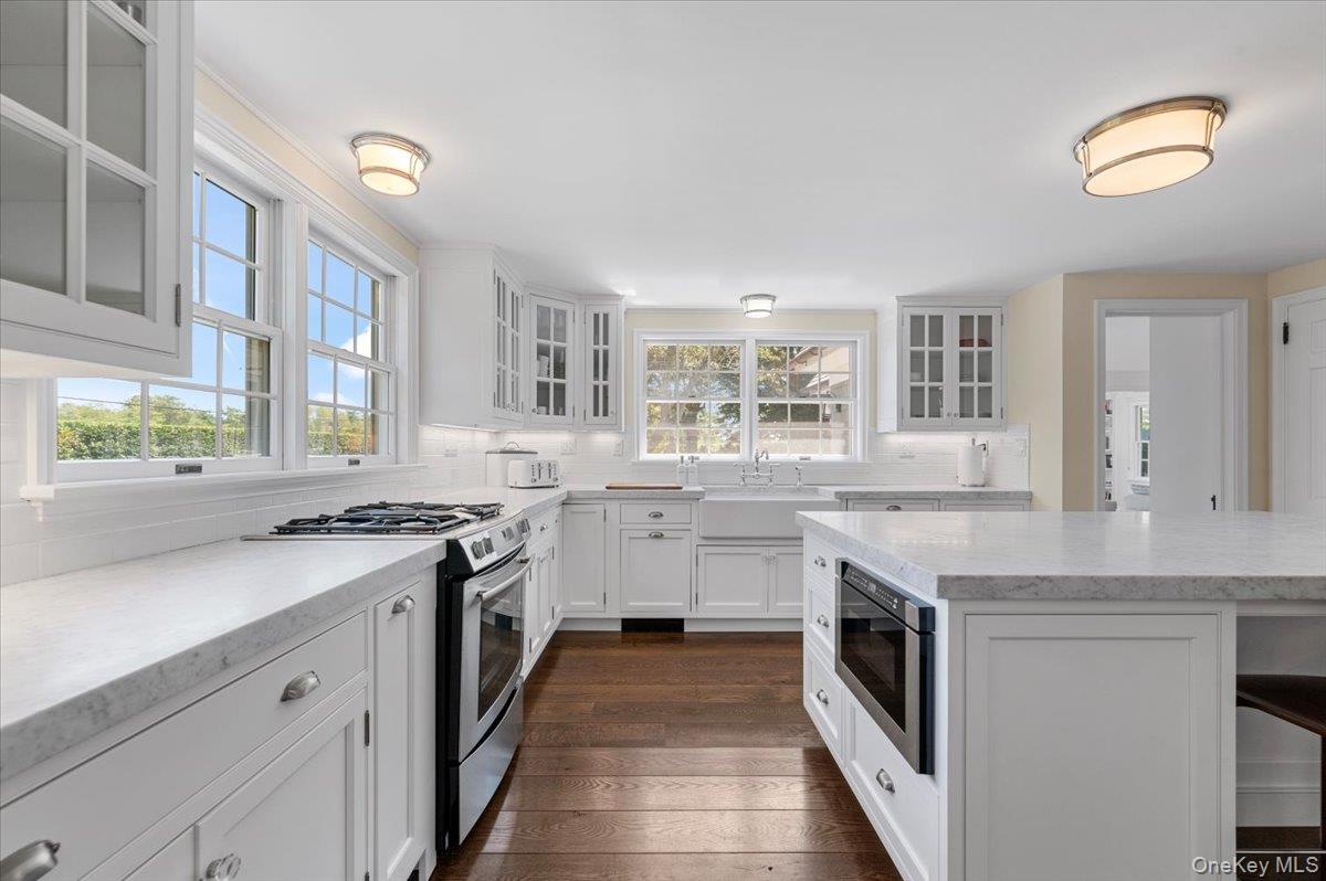 2 Strongs Lane Water Mill, NY 11976 - Photo 23 of 47 Kitchen with glass insert cabinets, appliances with stainless steel finishes, white cabinetry, and a breakfast bar area