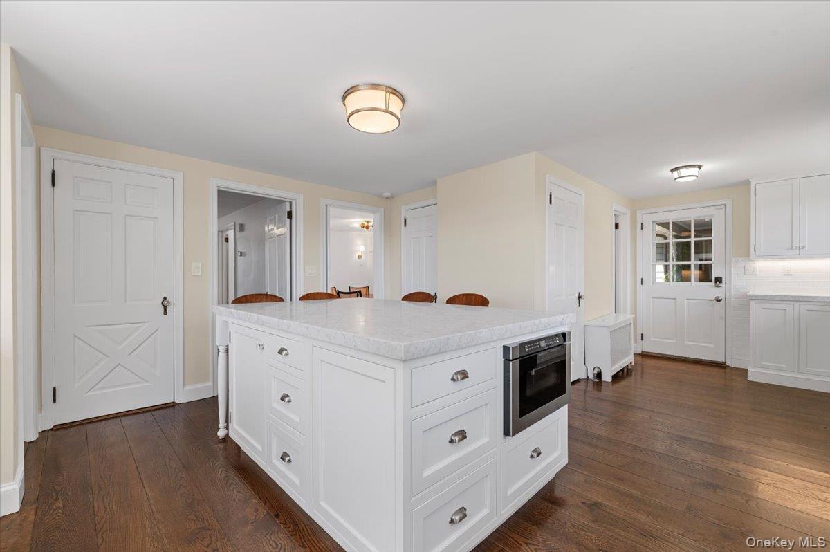 2 Strongs Lane Water Mill, NY 11976 - Photo 25 of 47 Kitchen featuring white cabinets, a breakfast bar area, dark wood-style floors, and tasteful backsplash