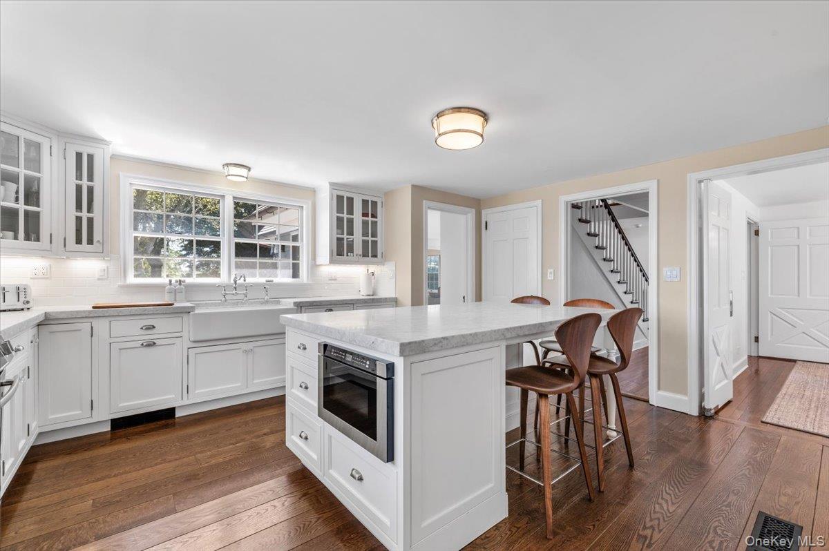 2 Strongs Lane Water Mill, NY 11976 - Photo 28 of 47 Kitchen with white cabinetry, backsplash, a kitchen bar, and glass insert cabinets