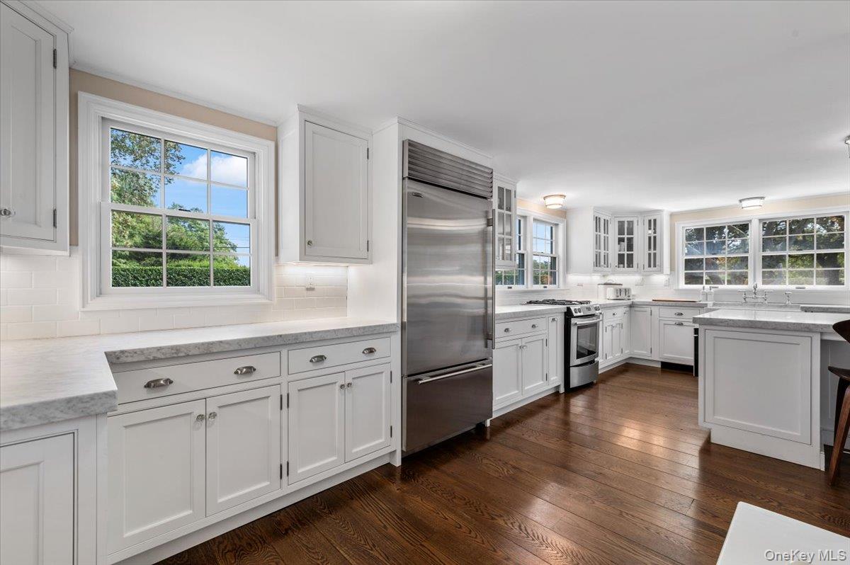 2 Strongs Lane Water Mill, NY 11976 - Photo 30 of 47 Kitchen with white cabinets, appliances with stainless steel finishes, light stone countertops, dark wood-style floors, and decorative backsplash