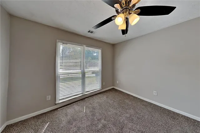 an empty room with a window and a ceiling fan