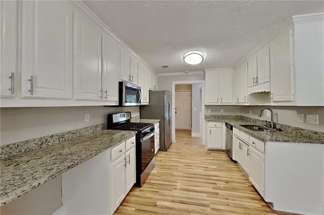 a large kitchen with granite countertop a sink and dishwasher a stove top oven with wooden floor