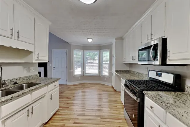 a kitchen with stainless steel appliances granite countertop a stove a sink and a microwave
