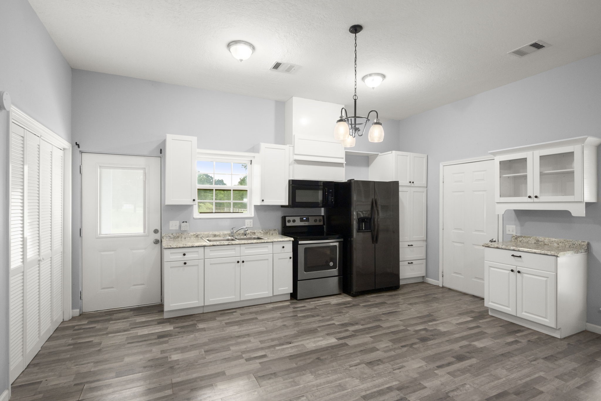 10871 Coaster Lane Conroe, TX 77306 - Photo 17 of 37 Plenty of room in this cozy kitchen to prepare a feast with views of the acreage and pond. Can you visulalize your breakfast/ dinning table in the open space? The door to the left leads to back patio, door to the right leads to covered parking.