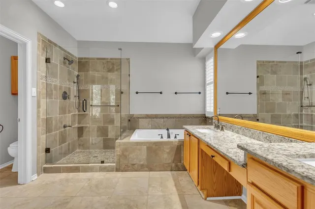 a spacious bathroom with a granite countertop tub sink shower and mirror