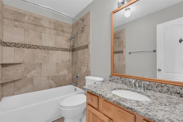 a bathroom with a granite countertop sink a toilet and shower