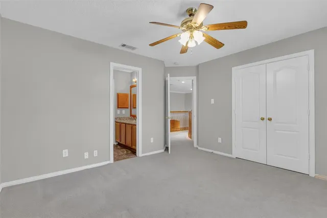 an empty room with closet and a ceiling fan