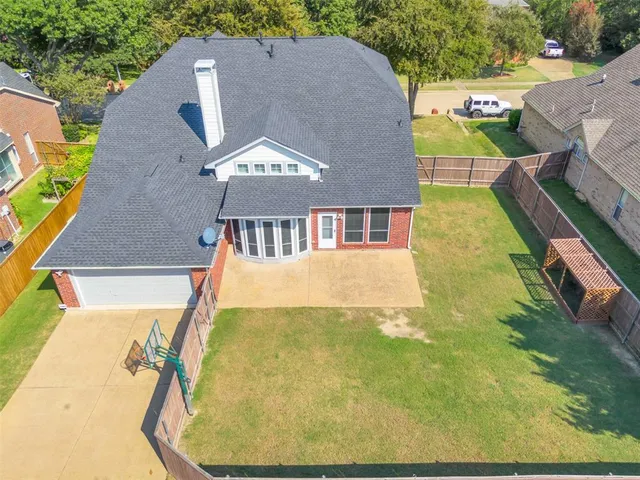 an aerial view of a house with swimming pool and large trees