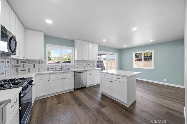 a large kitchen with a white cabinets and wooden floor