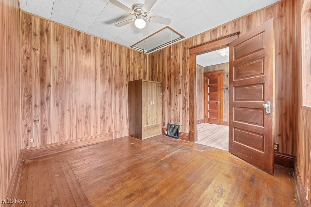 2725 Linwood Road Akron, OH 44312 - Photo 24 of 38 Spare room featuring ceiling fan, hardwood / wood-style flooring, and wooden walls