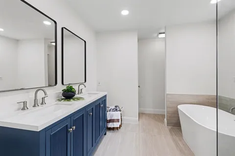 a bathroom with a double vanity sink and mirror with bathtub