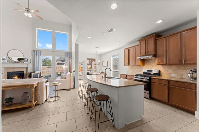 a kitchen with stainless steel appliances granite countertop wooden cabinets a sink dishwasher a dining table and chairs with wooden floor