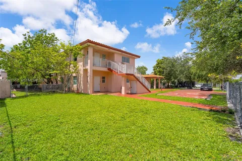 a view of a house with backyard and a tree