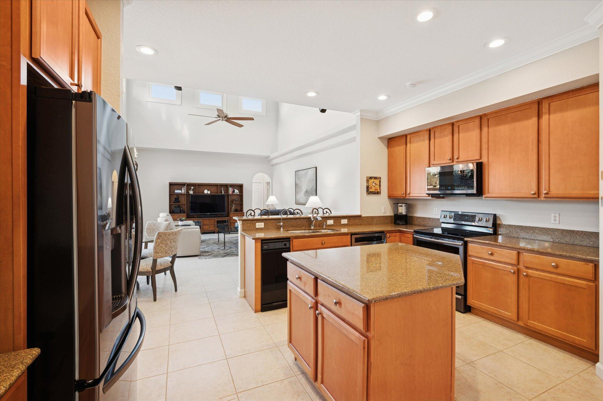 7299 Serrano Terrace Delray Beach, FL 33446 - Photo 11 of 39 a kitchen with stainless steel appliances granite countertop a refrigerator a stove a sink a oven and a refrigerator with wooden cabinets