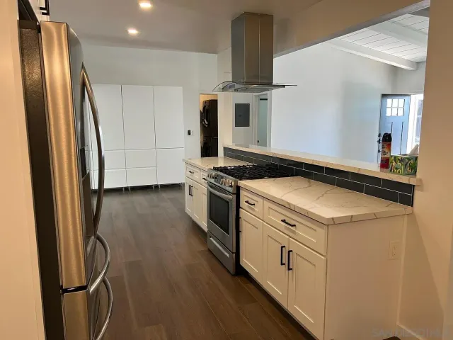 a kitchen with stainless steel appliances a refrigerator a stove and wooden floor