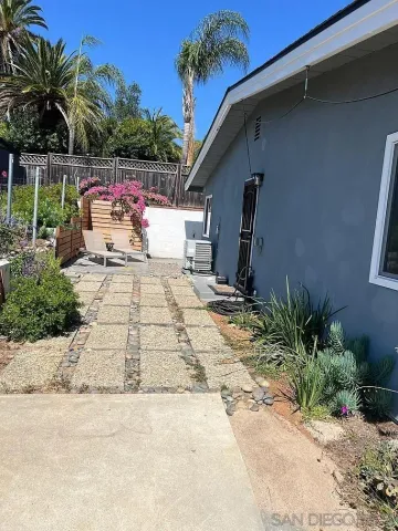 a backyard of a house with potted plants and palm trees