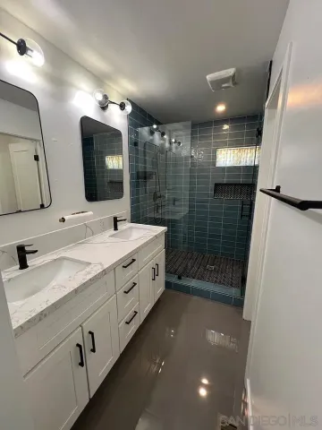 a bathroom with a double vanity sink mirror and shower
