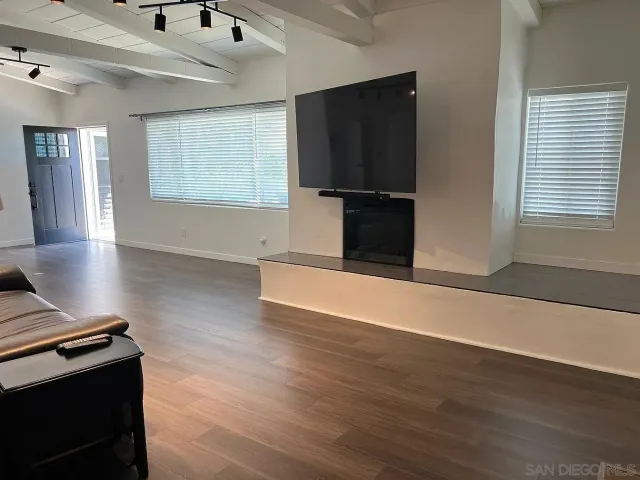 an empty room with wooden floor a fireplace and windows