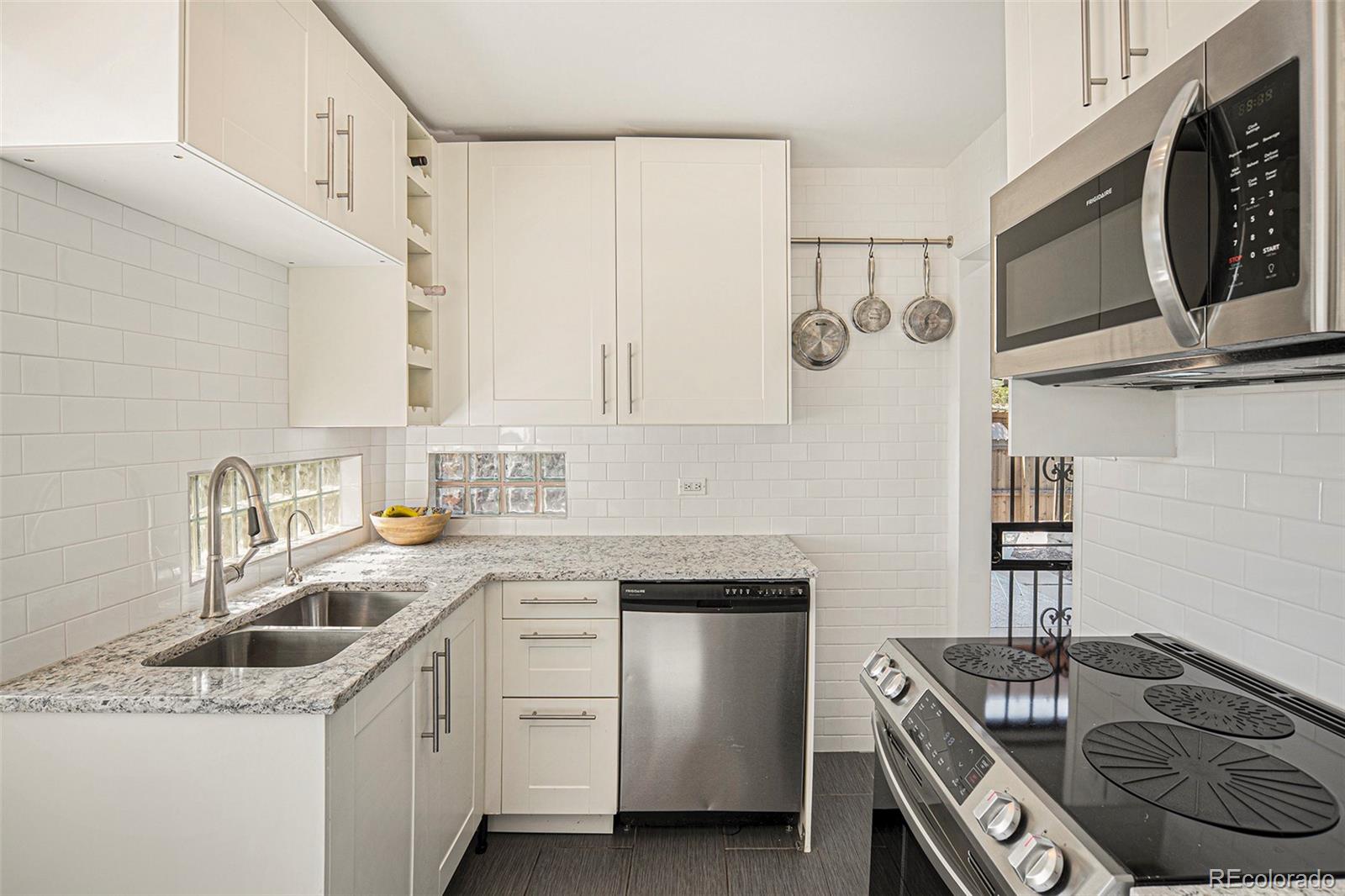 3621 Oneida Street Denver, CO 80207 - Photo 11 of 35 a kitchen with stainless steel appliances granite countertop a sink stove and cabinets