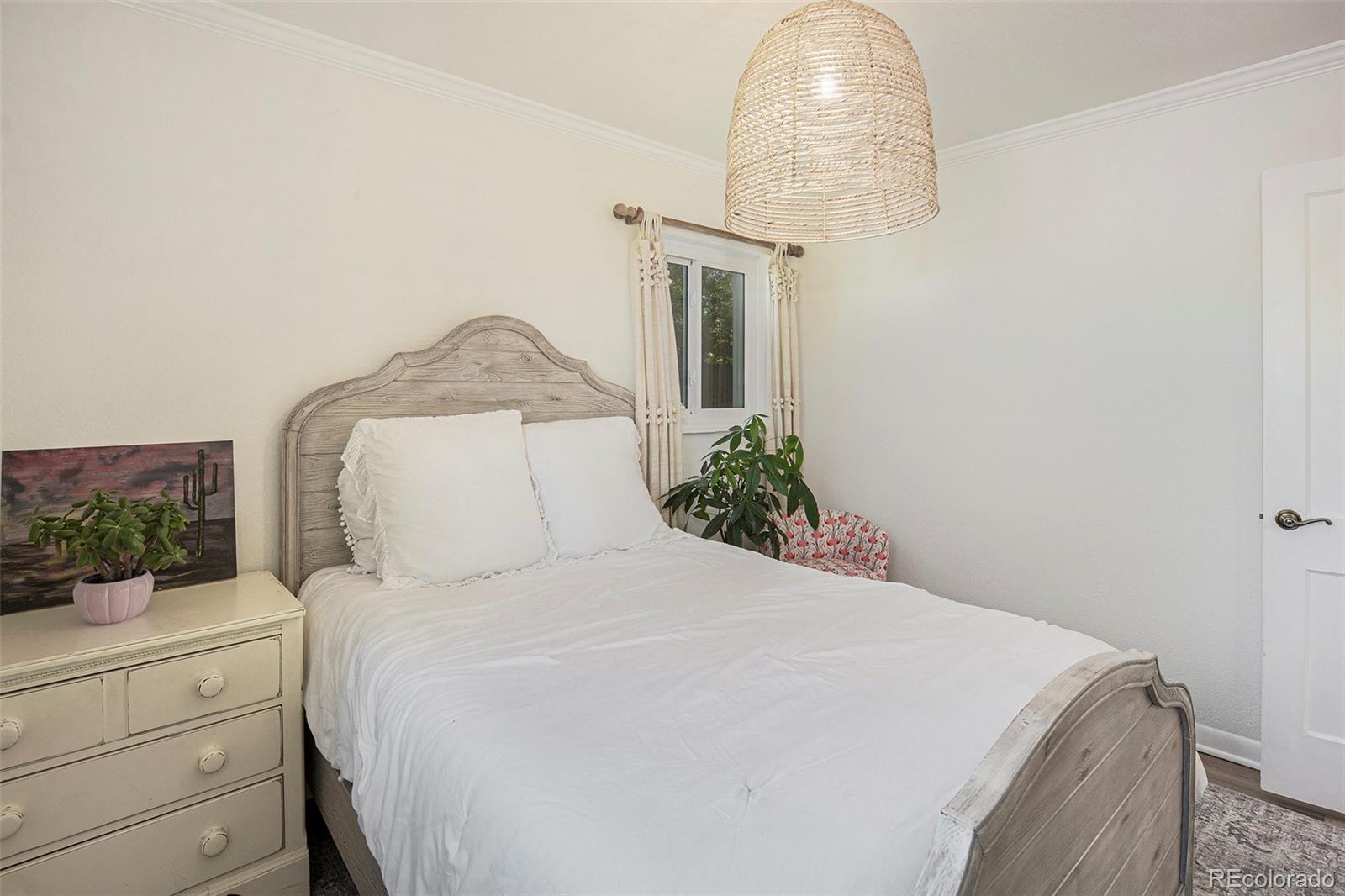 3621 Oneida Street Denver, CO 80207 - Photo 13 of 35 a bedroom with a bed and a chandelier