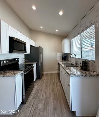 a kitchen with stainless steel appliances granite countertop a stove top oven a sink dishwasher a refrigerator and a microwave