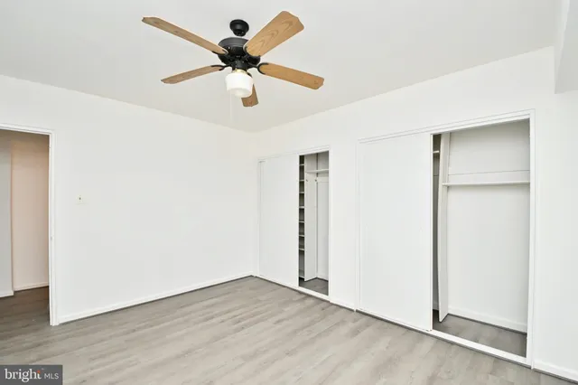 an empty room with wooden floor and a ceiling fan