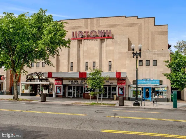 a front view of multi story residential apartment building with a yard and seating space