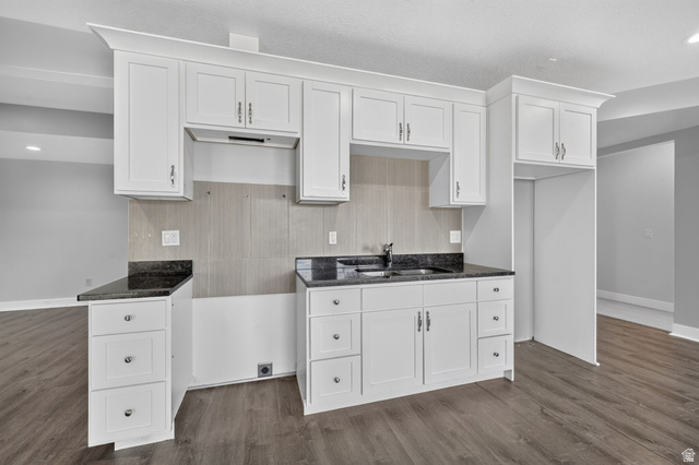 1002 West Temple Rim Lane Payson, UT 84651 - Photo 46 of 68 Kitchen featuring white cabinetry, dark stone countertops, a stainless steel sink with a dark faucet, a light gray tile backsplash, and wood-finish flooring