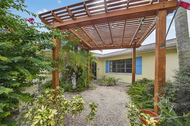 a view of a white house with a large tree and wooden fence
