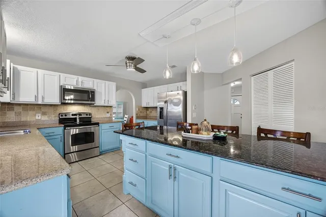 a kitchen with stainless steel appliances kitchen island granite countertop dining table chair and cabinets