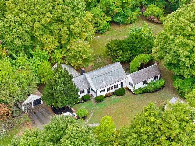 an aerial view of residential house with outdoor space and trees all around