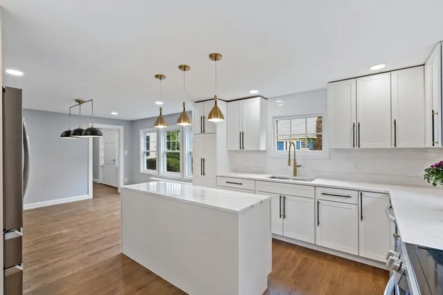 a large white kitchen with a sink and dishwasher a refrigerator with wooden floor