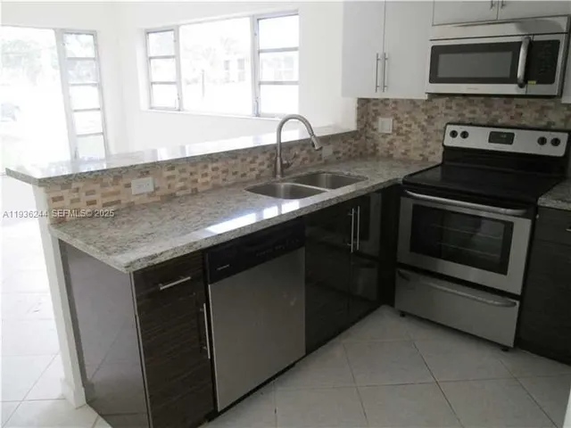 a kitchen with granite countertop white cabinets and stainless steel appliances