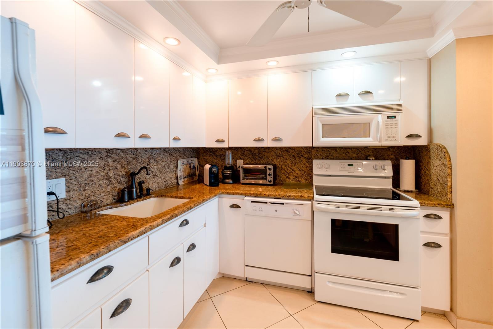2101 South Ocean Drive, Unit 2002 Hollywood, FL 33019 - Photo 11 of 23 a kitchen with granite countertop white cabinets and white appliances